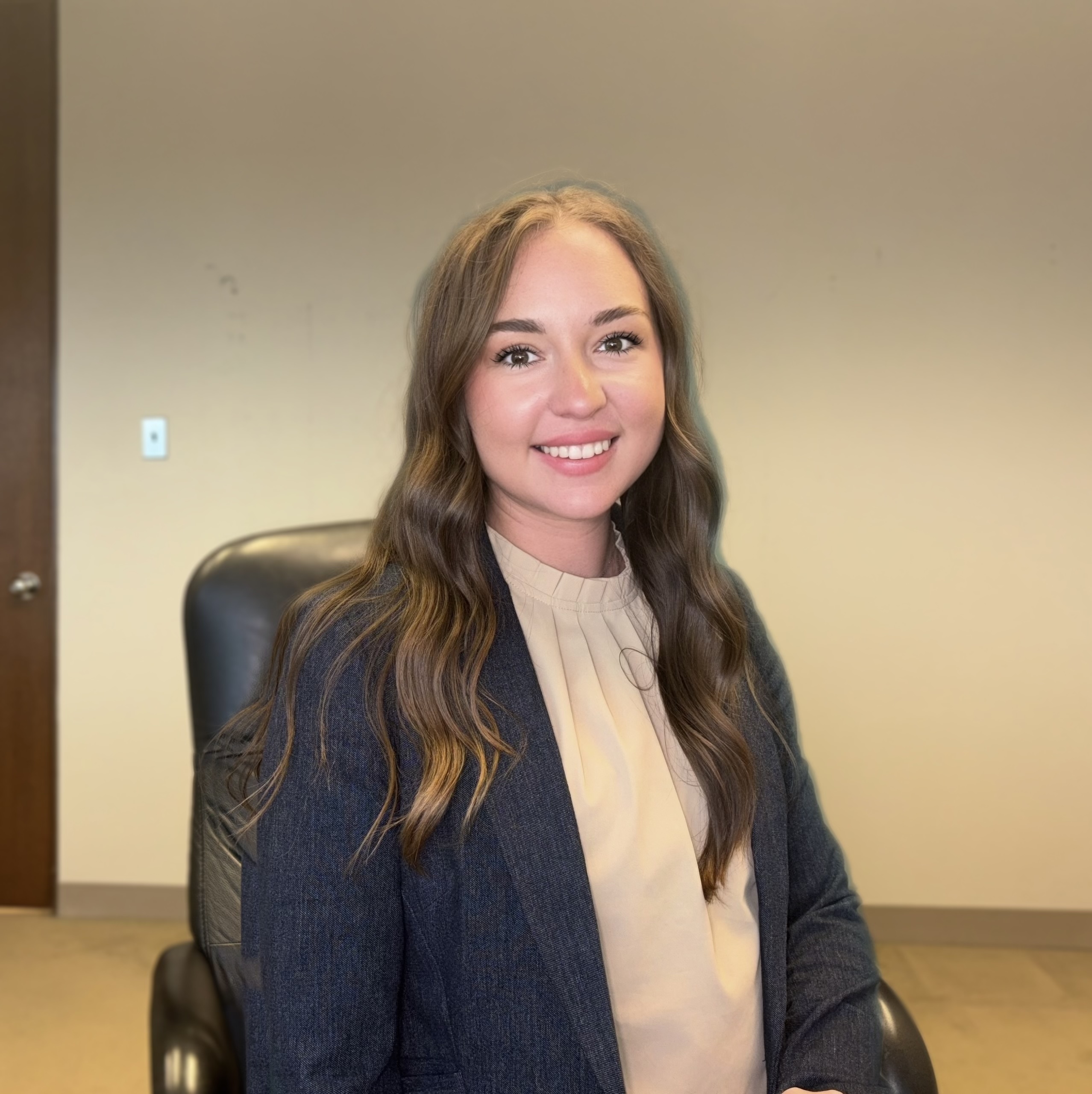 Student Manager Brooklyn Thomas is smiling in an office chair,