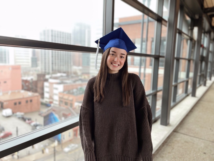 Caroline Kucko in commencement cap standing near window