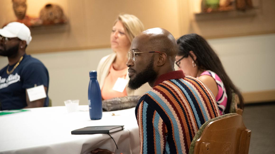 Doctoral students sitting around table engaged while istening to lecture.