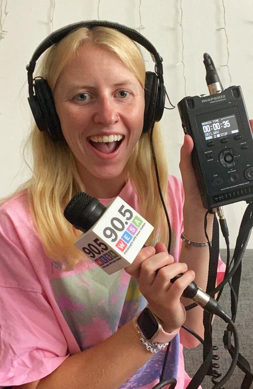 Pictured is Isabella Abbott wearing headphones and holding a WESA 90.5 microphone.