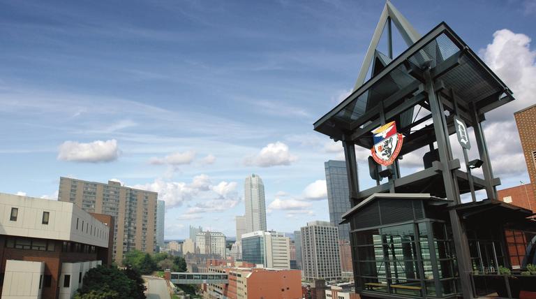 Duquesne campus skyline with Power Center tower and Duquesne seal and coat of arms shield emblem.